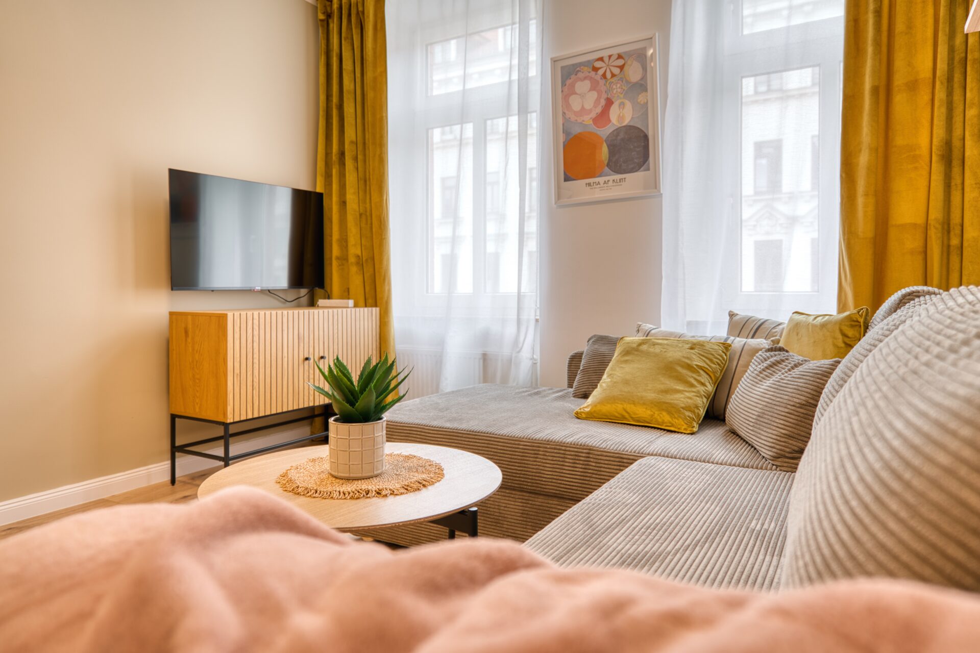 Wohnzimmer mit TV und einem elegantem Cordsofa mit stilvollen Kissen. Fotograf für Immobilien.