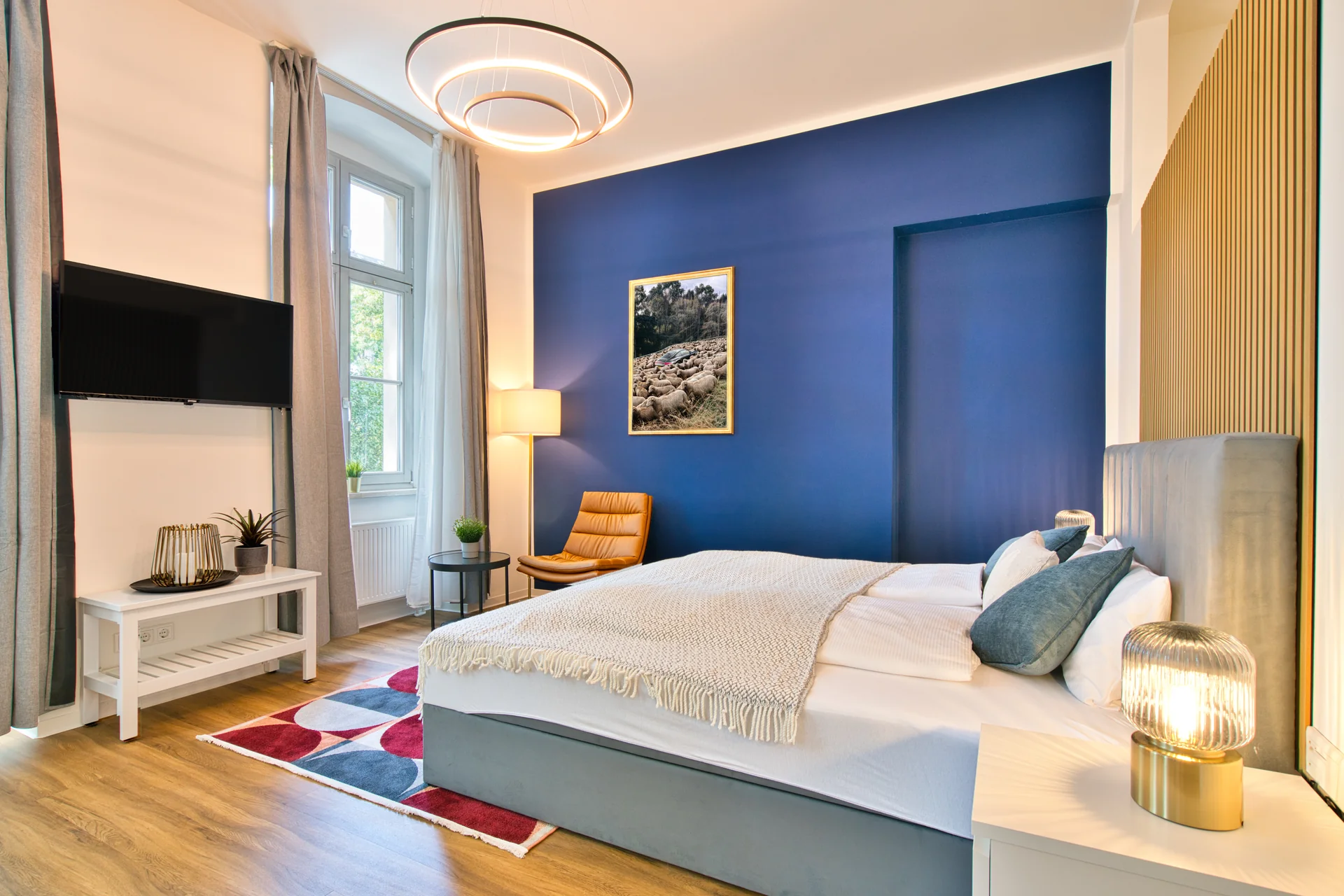 Schlafzimmer einer Ferienwohnung mit TV, King-Size Bett , Sessel und Dekoelementen