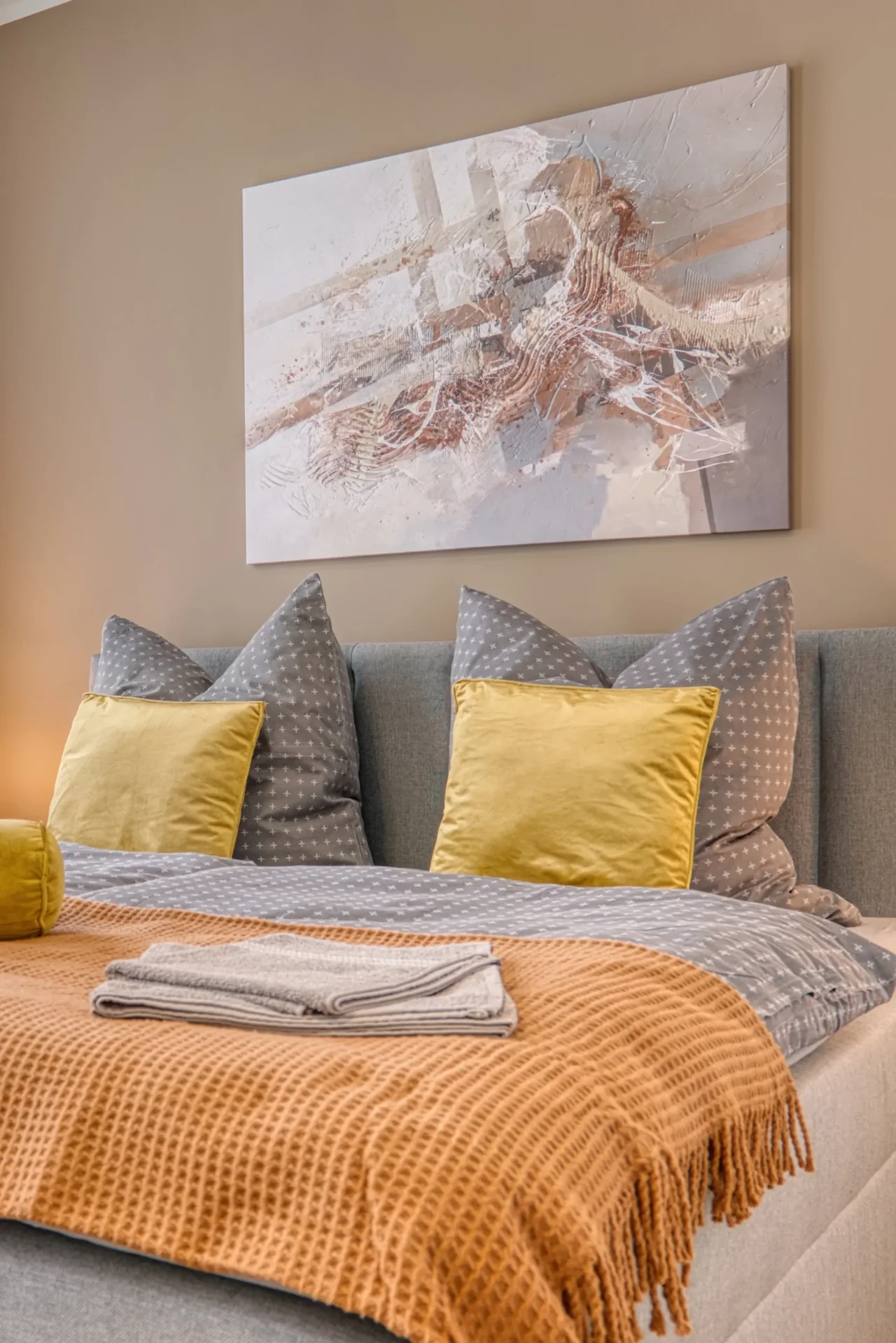 Gemütliches Bett mit Kopfkissen und Decken. Ein Bild an modernes Bild an der Wand.